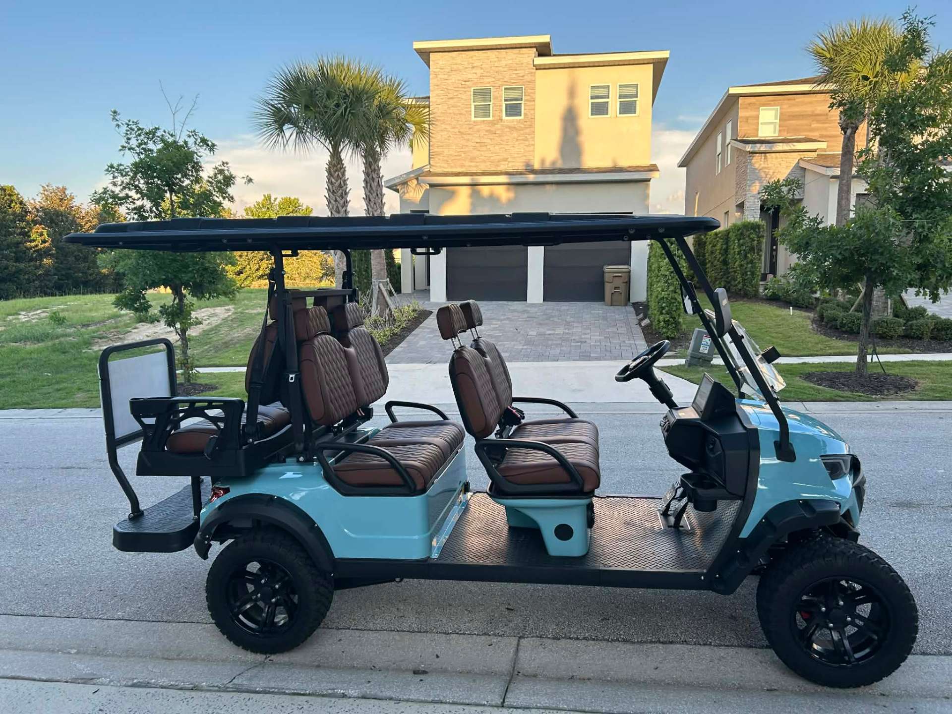 Teal 6-seater luxury golf cart with brown quilted seats parked at a Reunion Resort vacation home