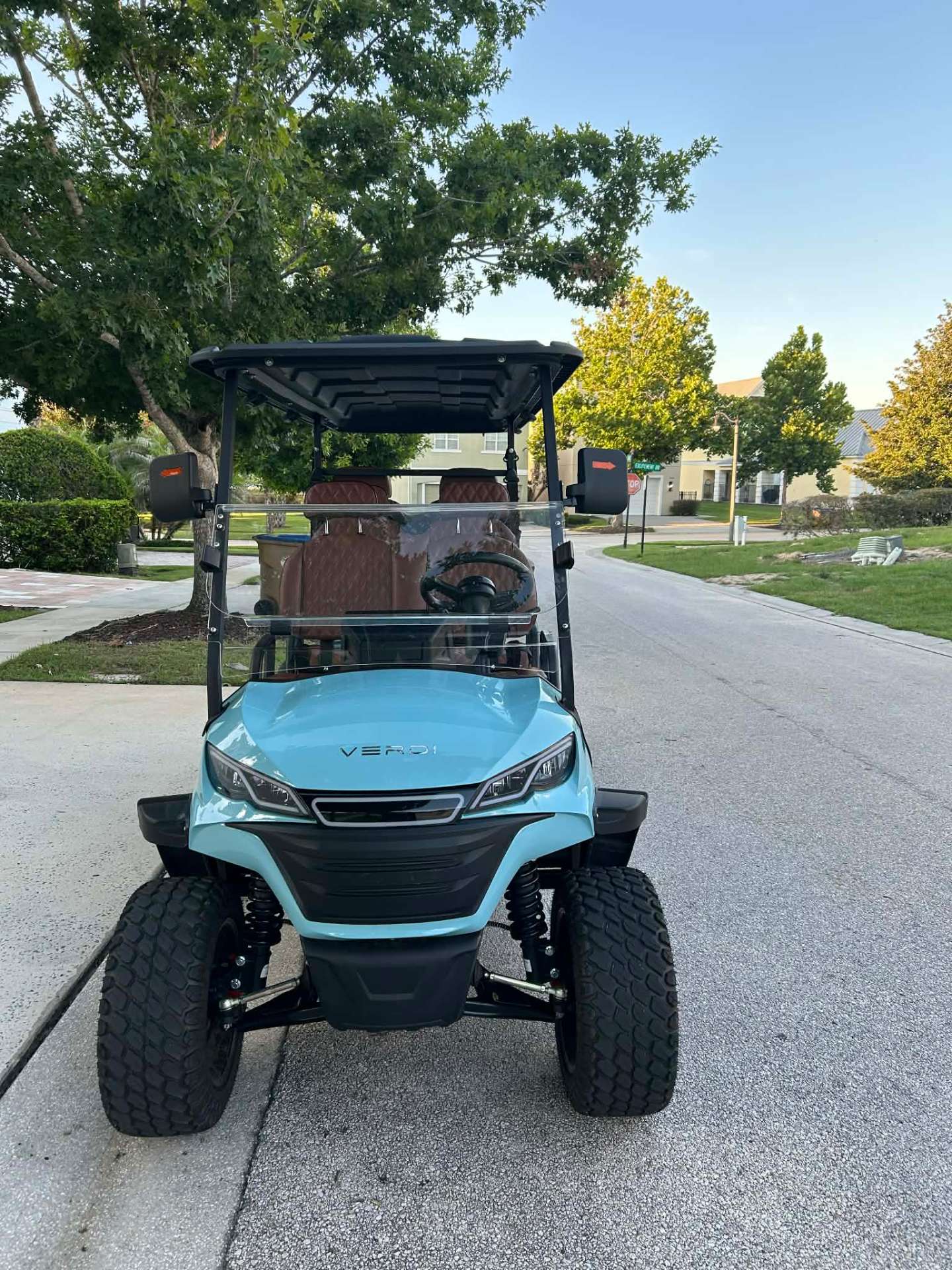 Front view of teal Verdi luxury golf cart parked on a Reunion Resort street at golden hour